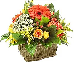 Basket of gerberas, roses and mixed flowers in warm colors