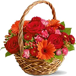 Basket of roses, gerberas and/or daisies and mixed flowers in warm colors