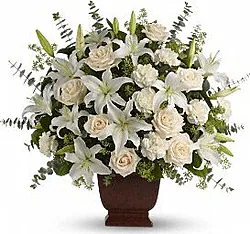 Delicate funeral arrangement of roses, lilies and mixed flowers