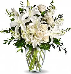 Funeral Roses, Lisianthuses, and Lilies arrangement decorated with seasonal greenery
