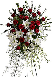 Funeral spray of red roses and delicate lilies and mixed flowers