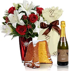 Rose rosse e gigli o lilium dai toni chiari con pandoro e spumante