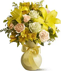 Rose e Lilium gialli confezionati con verde misto e fiori decorativi a tono